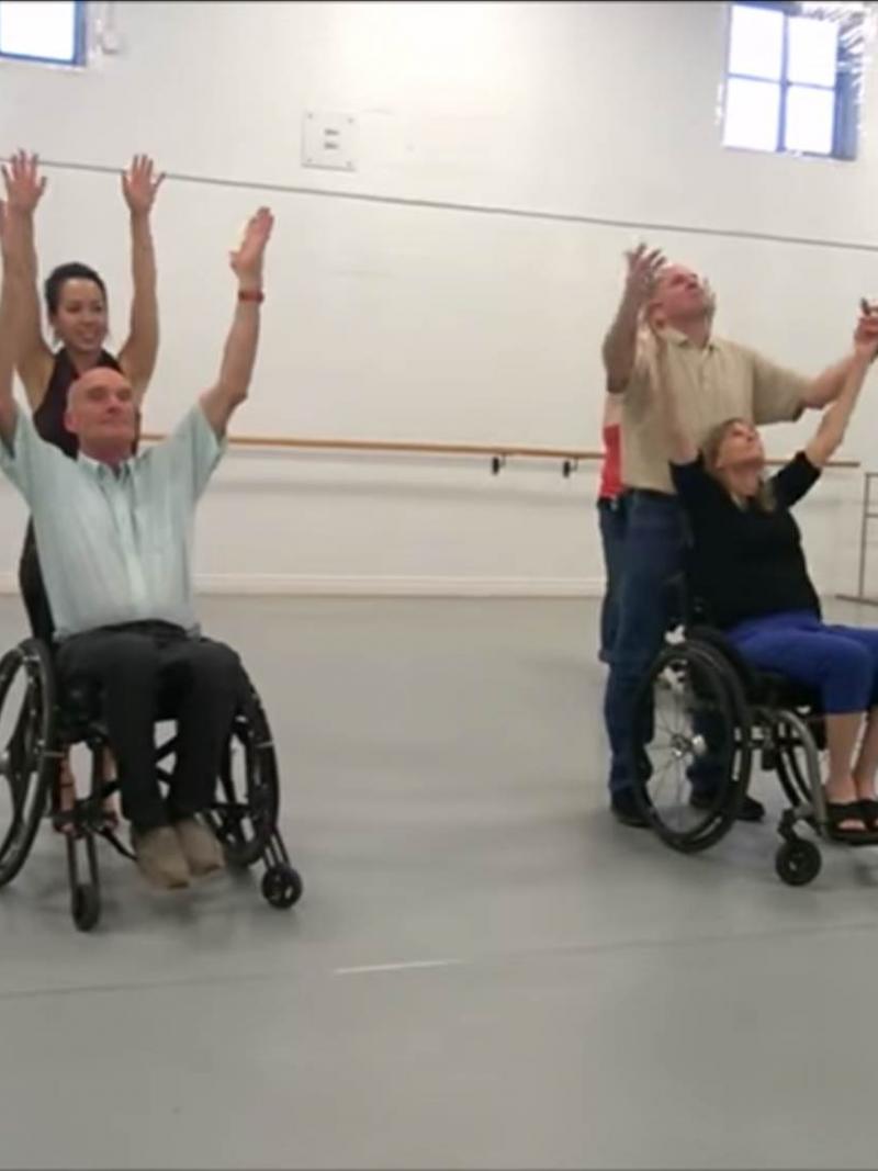 Group of people in wheelchairs and standing dancing