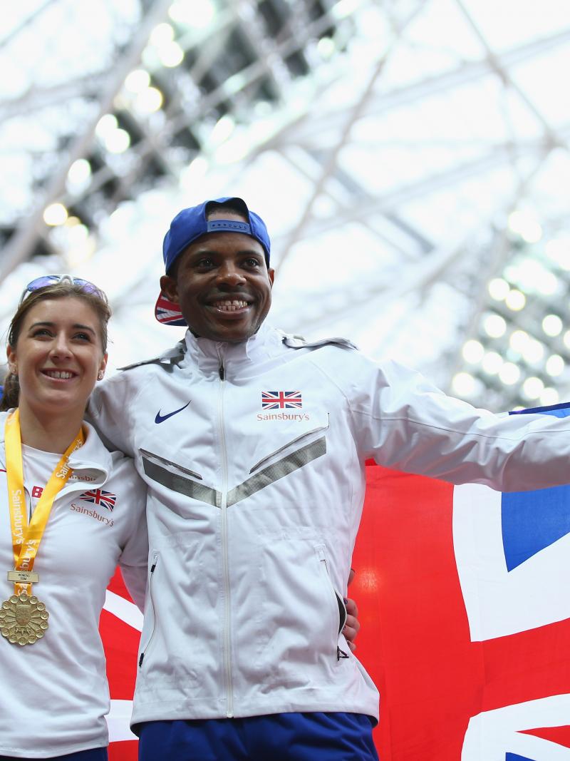 Man and woman on podium with a medal around her neck and a British flag