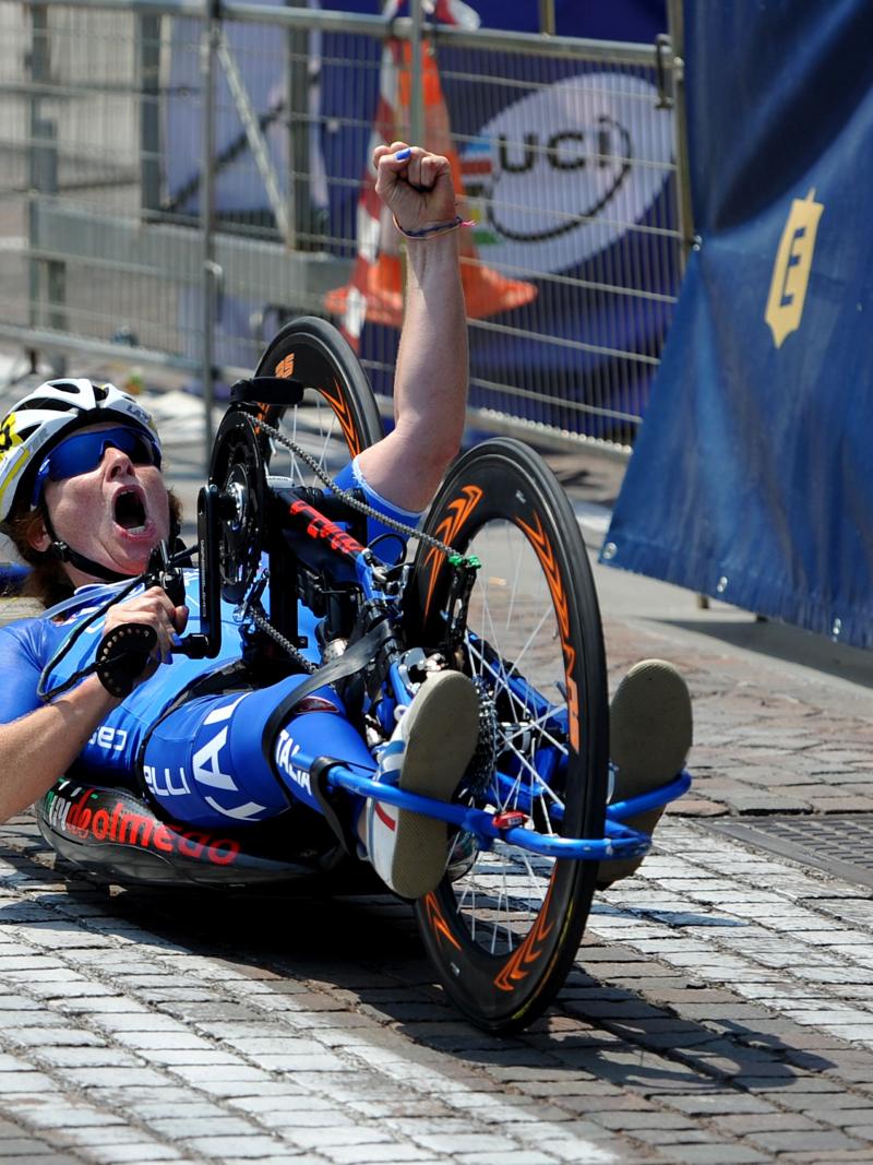 Woman on handbike crossing a finish line, celebrating