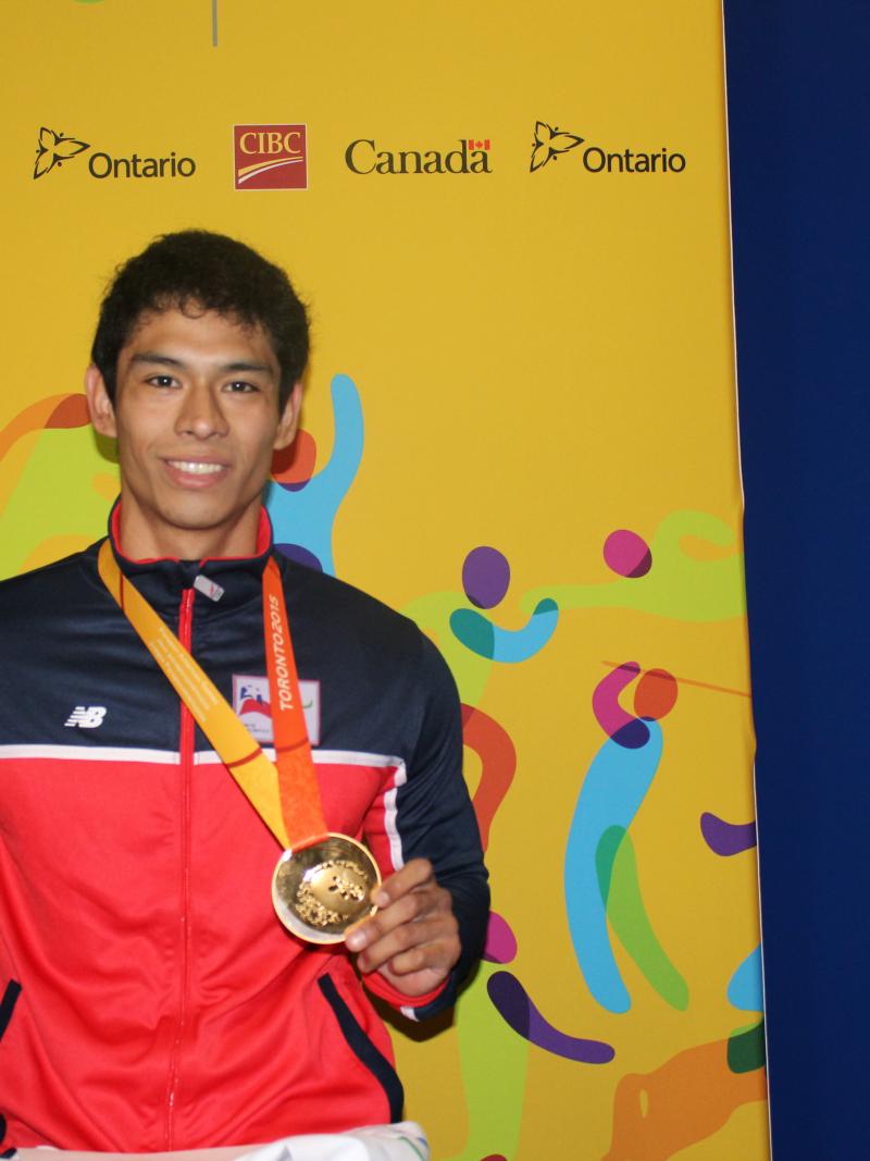 Jorge Carinao Cárdenas claims gold on the first day of powerlifting at the Toronto 2015 Parapan American Games on Saturday (8 August). He faces the camera holding the TO2015 mascot and his gold medal.