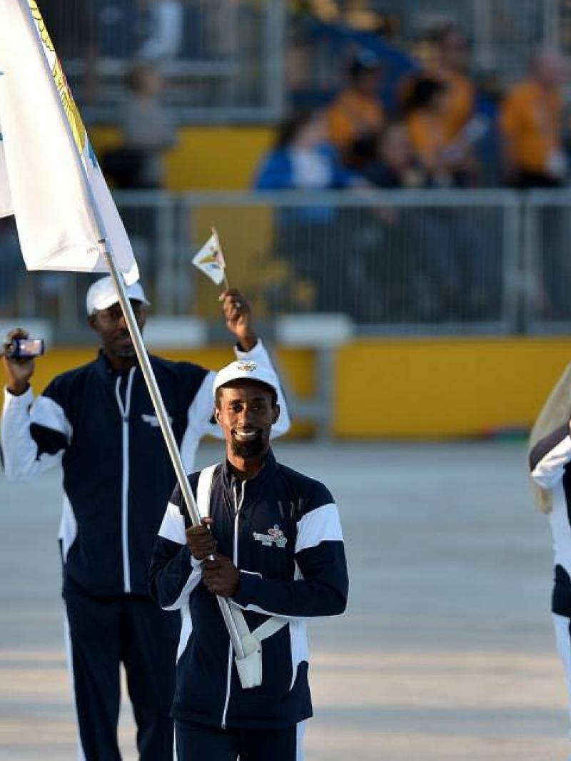 Man in a staduim, waving a flag followed by two other people