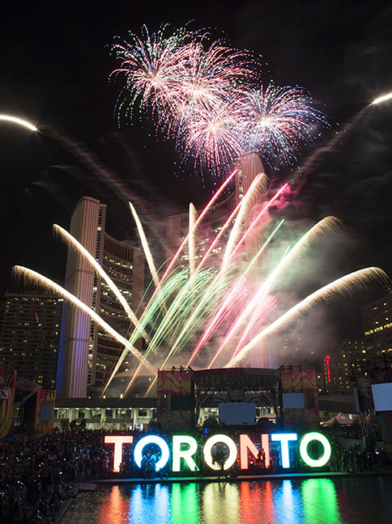 Fireworks in different colors illuminate the night above the 3D Toronto sign