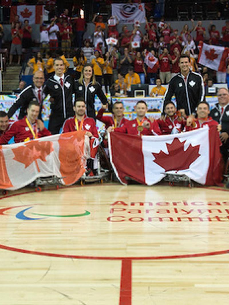 Team photo of a celebrating group of men sitting in wheelchairs, showing Canadian flags