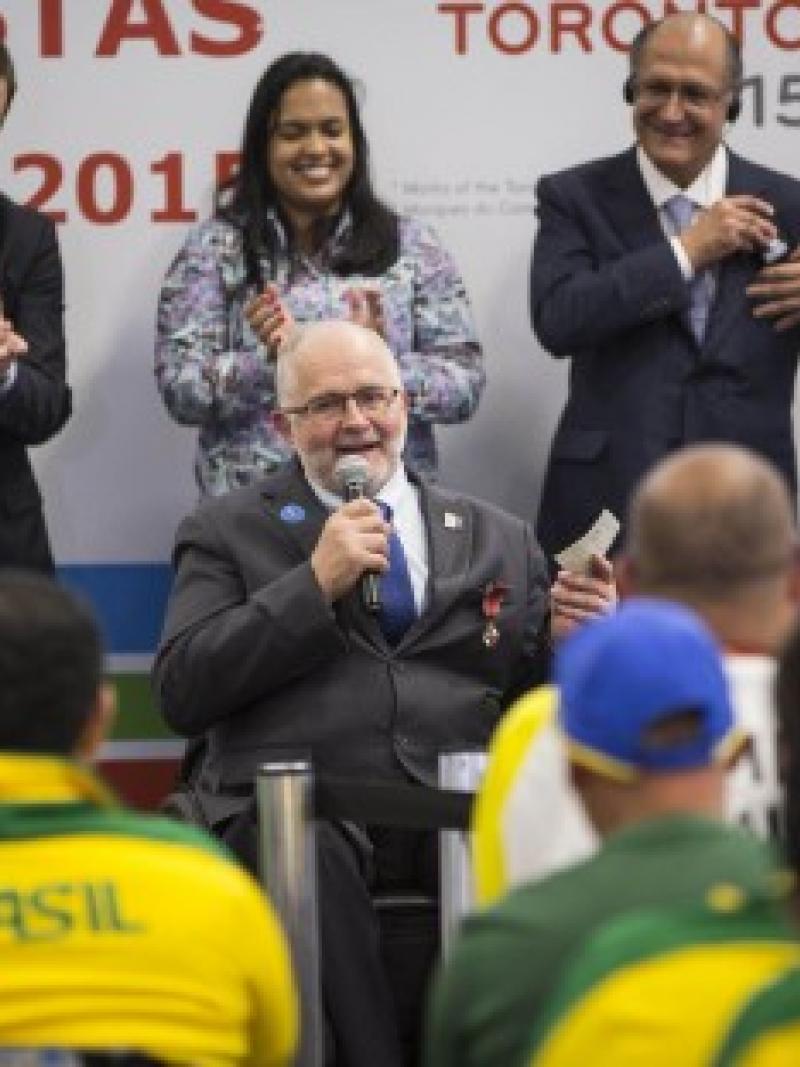 Man in wheelchair talking, people listening to him, applauding