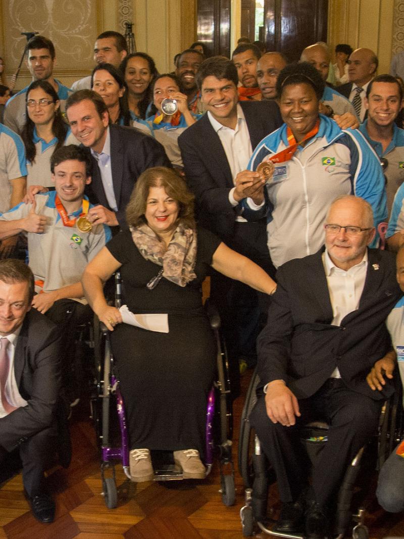 Group shot of athletes in Brazilian  team uniforms and some people in suits.