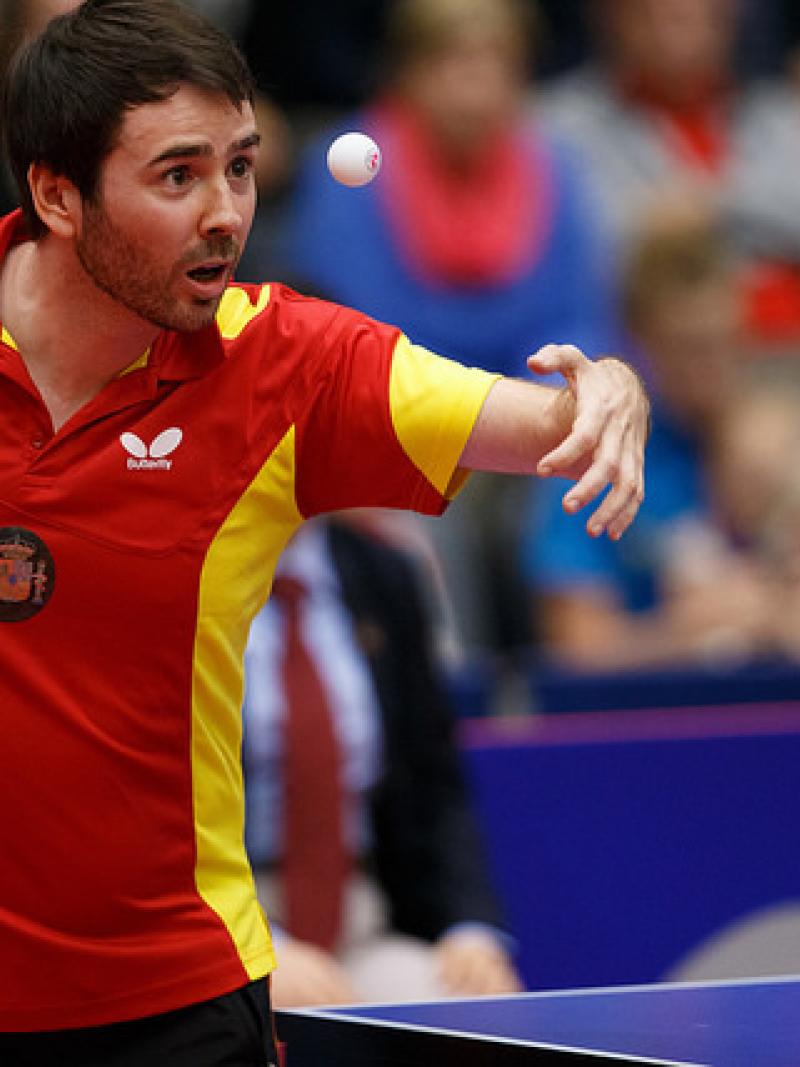Man in red jersey focusing on a table tennis ball