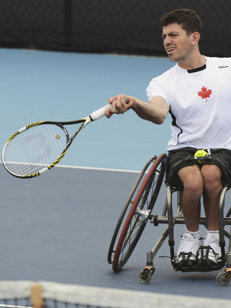 Man in wheelchair returns a tennis ball