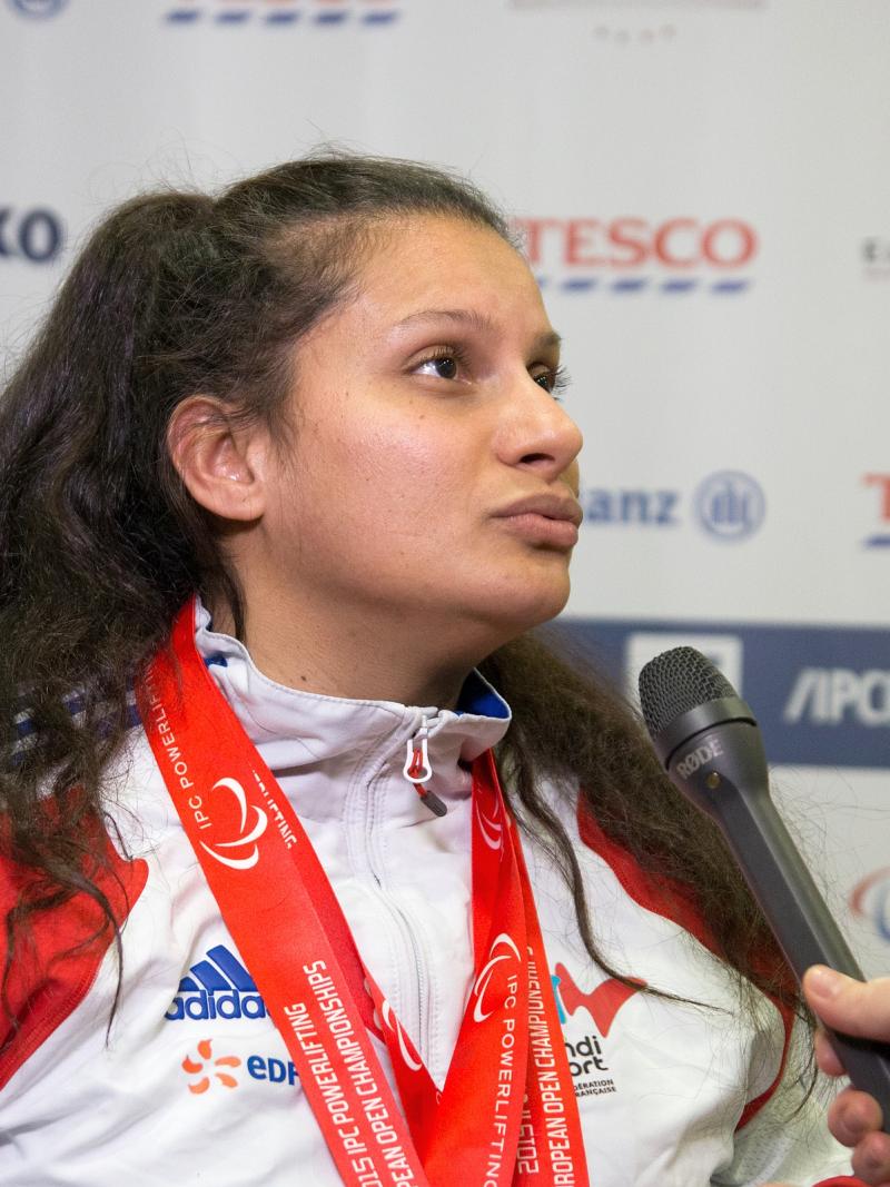 Upper body of woman in front of branded background, microphone