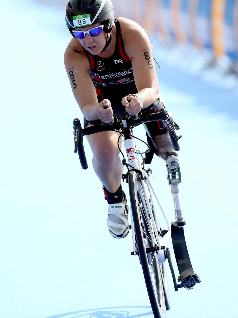 a female in black clothing and a black helmet riding a bicycle