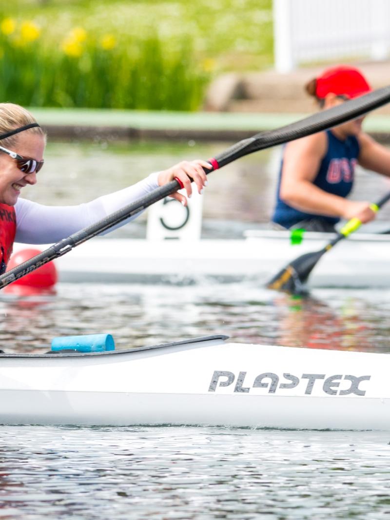 a photo showing the top half of a lady in a canoe wearing a white top, life jacket and sunglasses