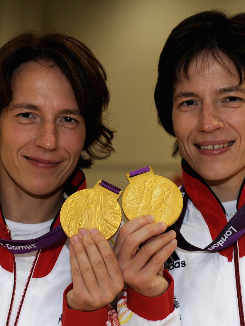 A shot of the upper half of two women holding two Paralympic gold medals
