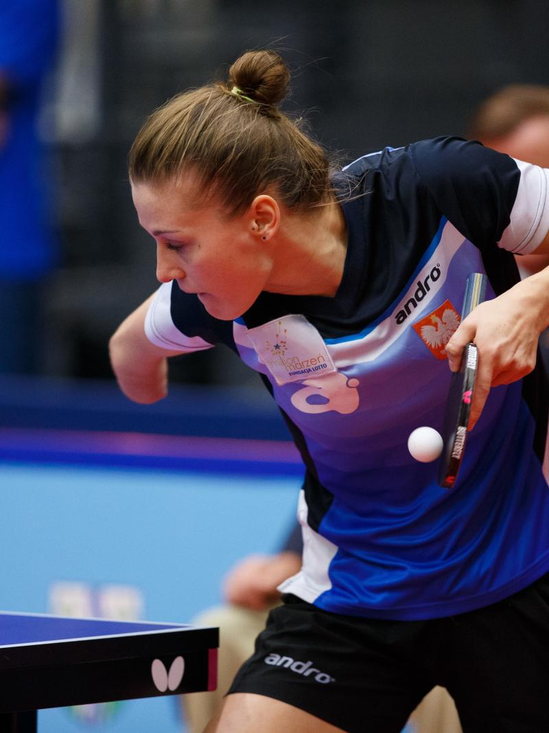 a female wearing a navy and blue shirt playing table tennis