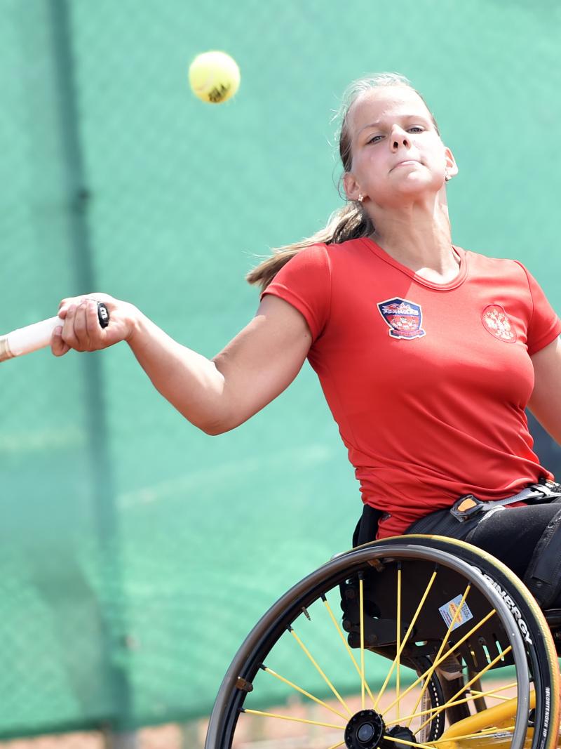 Girl in wheelchair hits a forehand return.