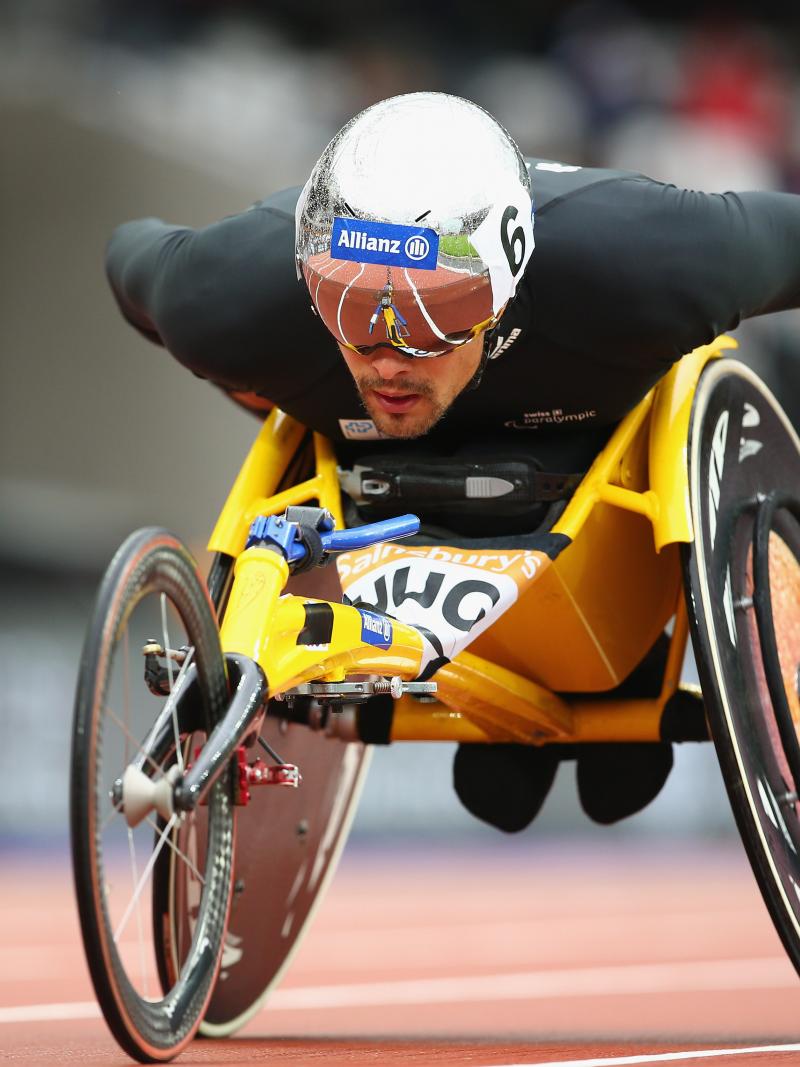 a male wearing black and a helmet racing in a wheelchair
