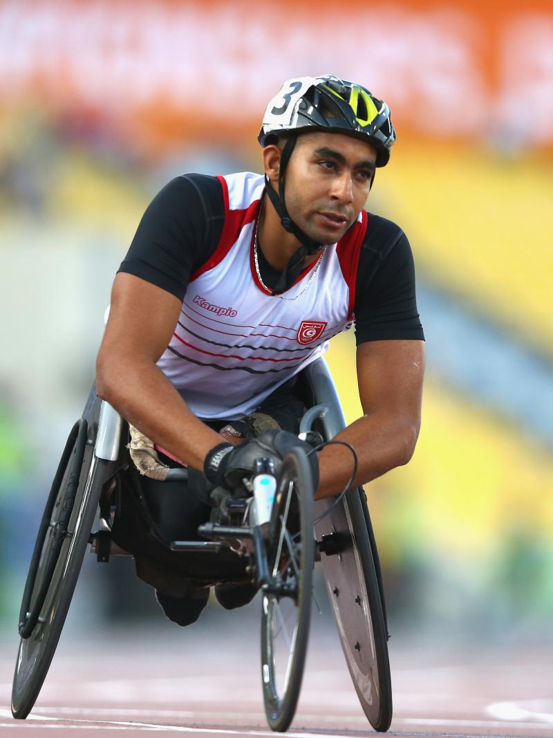 a male from Tunisia wearing a helmet and racing in a wheelchair