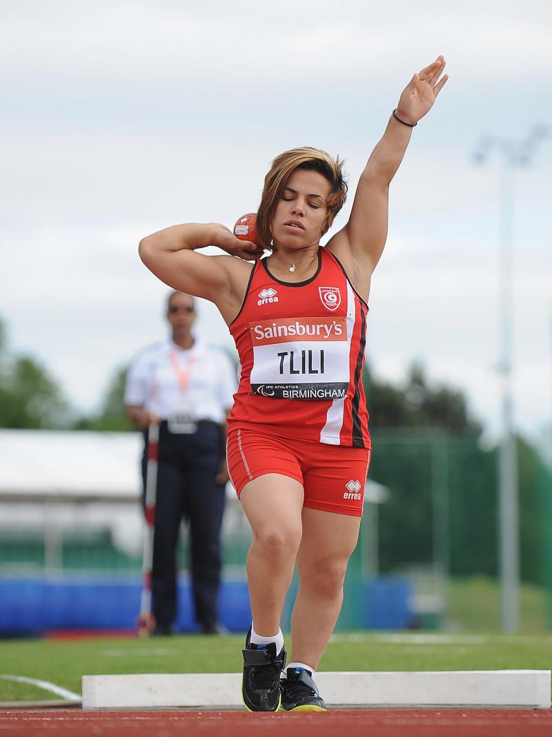 a female from Tunisia wearing red and competing in the shot put