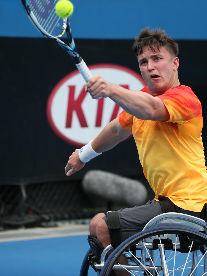 Man in wheelchair, hitting a ball with a tennis racket