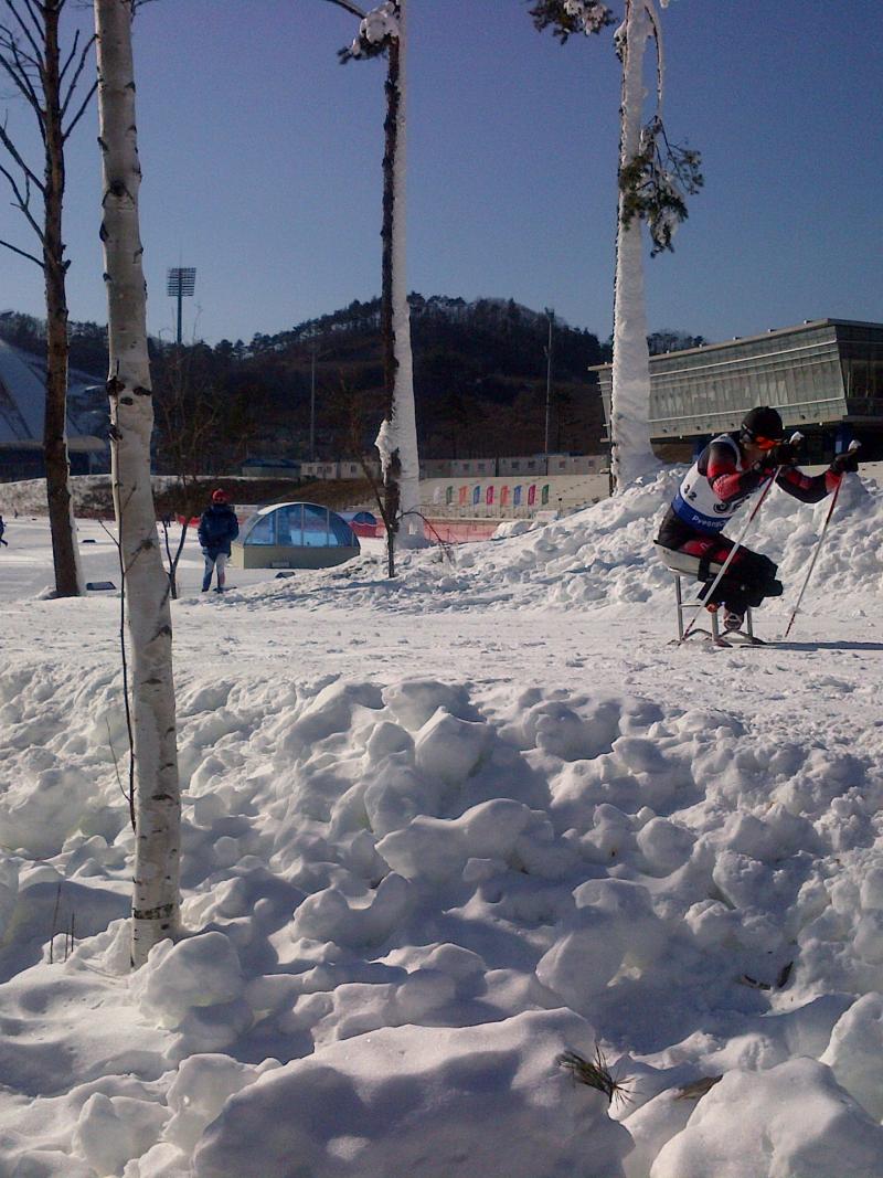 View on a slope with sit skier passing