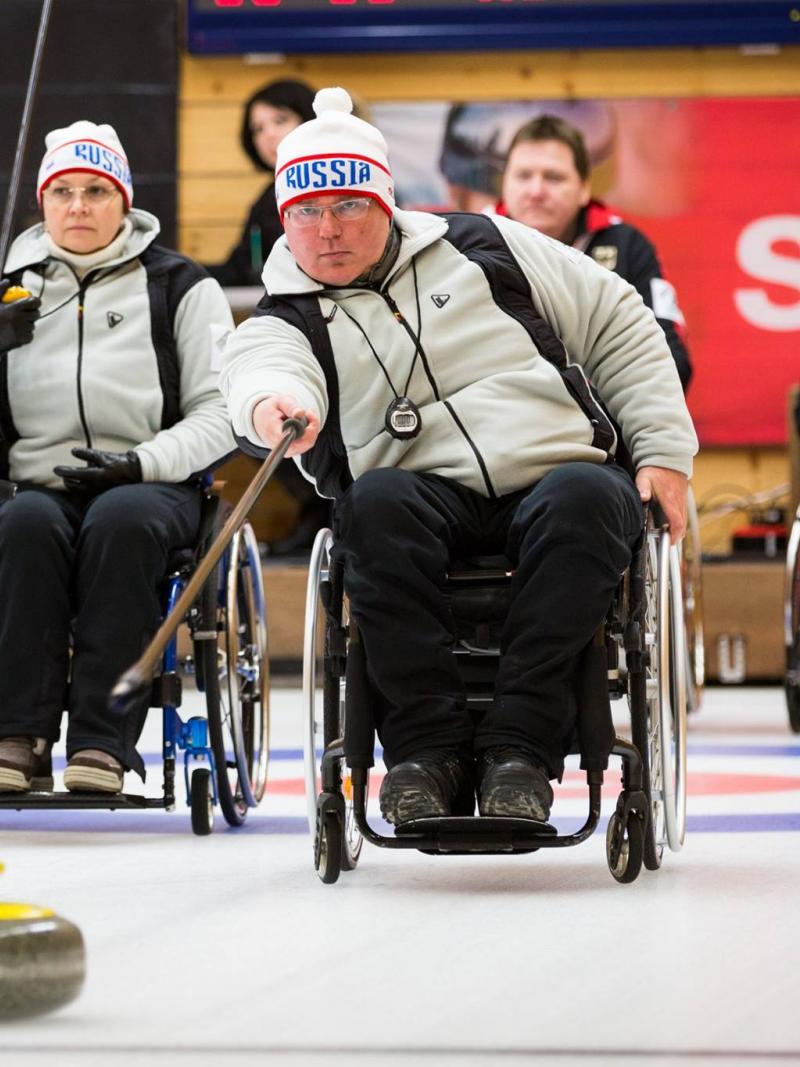Wheelchair curler on the ice with team in the background