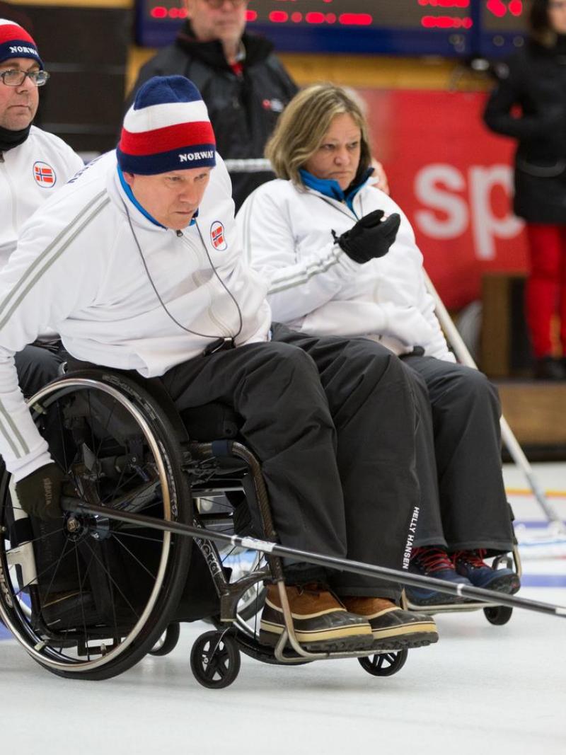 Wheelchair curler on the ice with team in the background