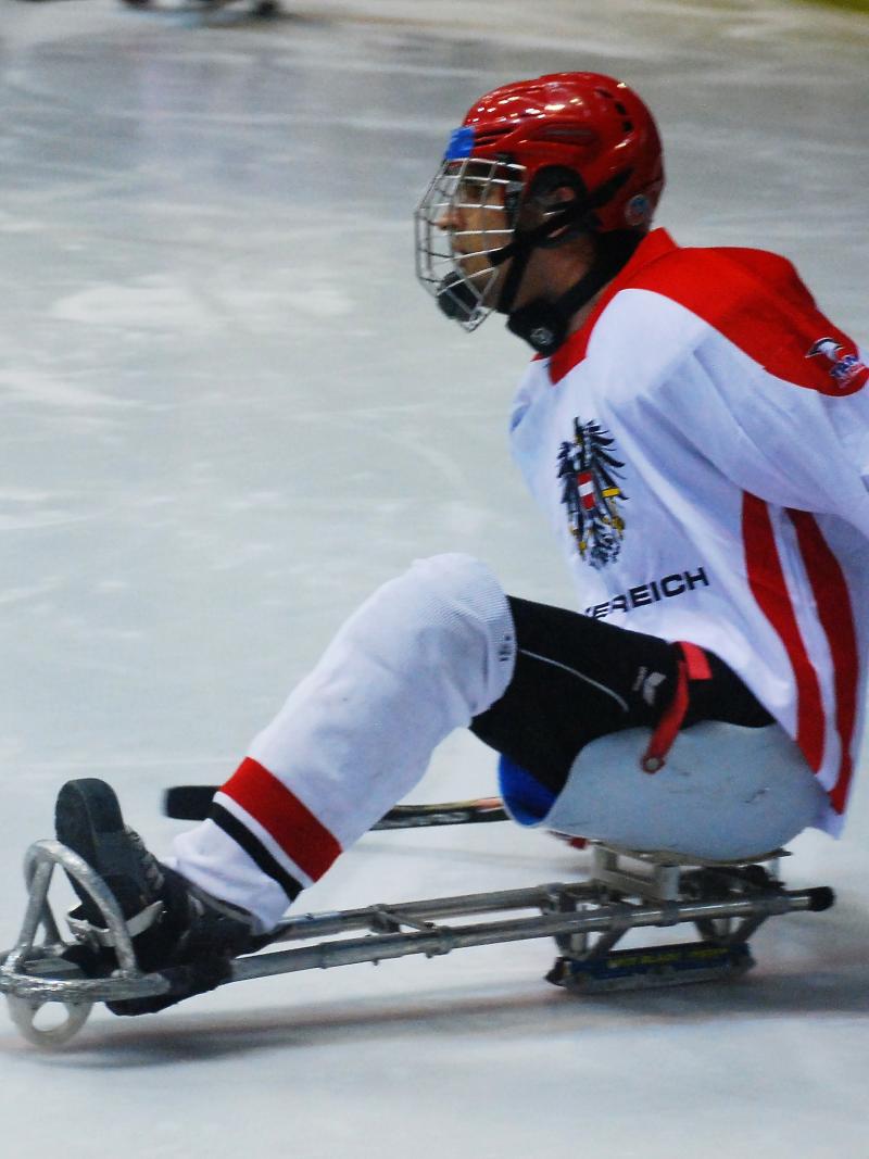 Ice sledge hockey player in red and white jersey on the ice