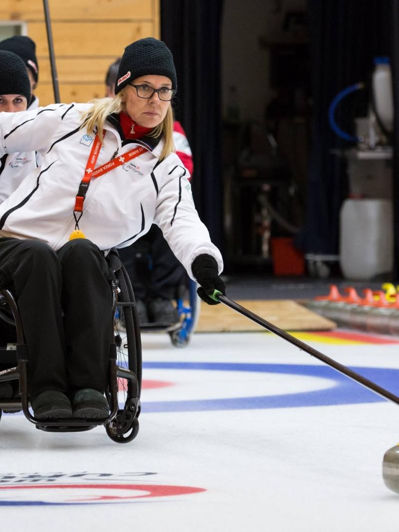 Wheelchair curler on the ice with team in the background