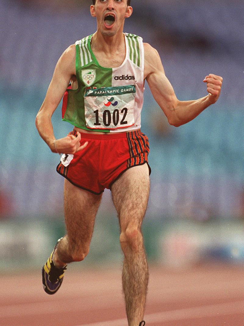 Man in running clothes, crossing a finish line, celebrating