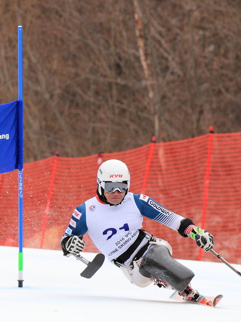 Man in a sit ski passing a gate