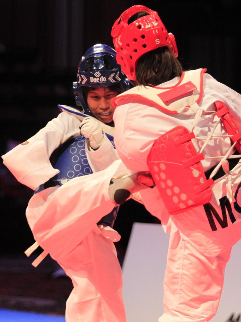 A taekwondo athlete kicks her female opponent 