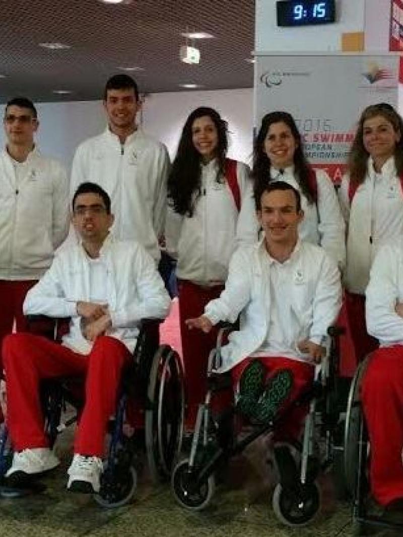Group shot of athletes standing and in wheelchairs at an airport.