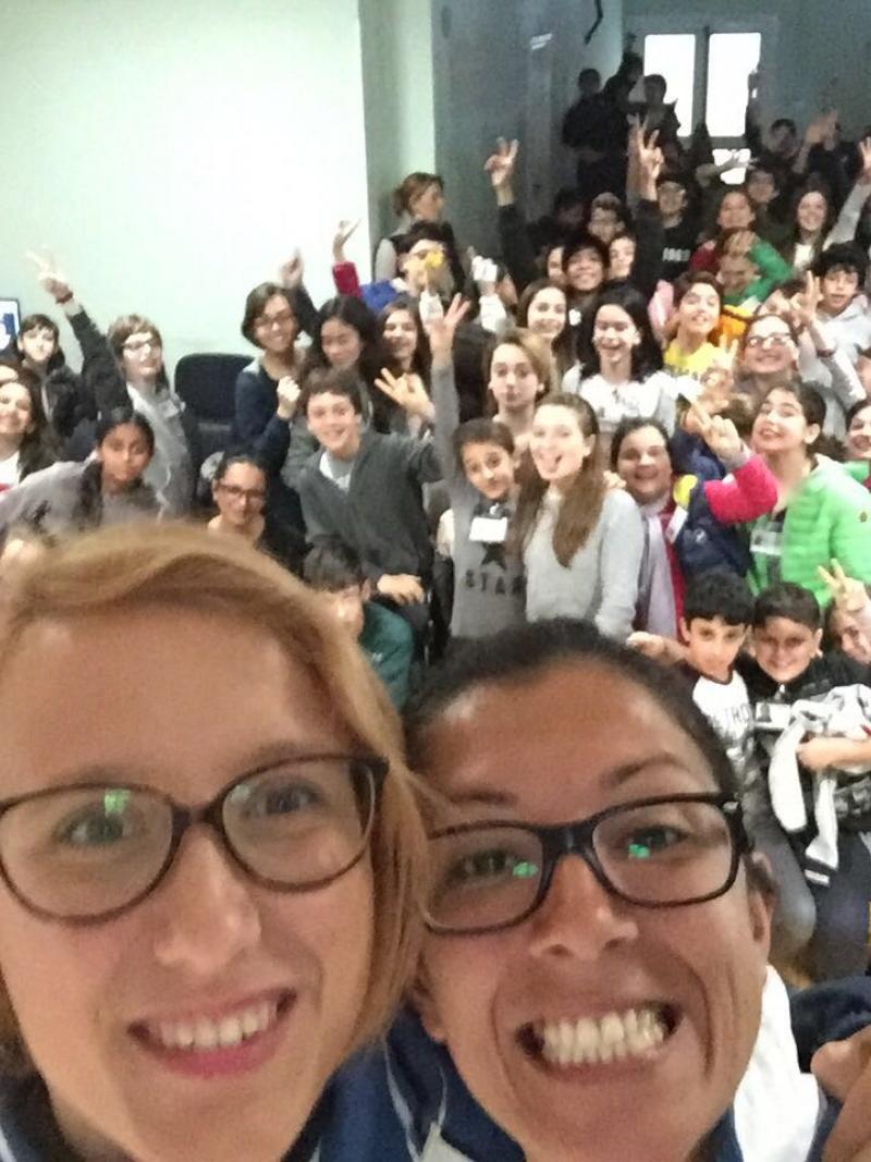 Selfie of two women smiling with many kids in the background