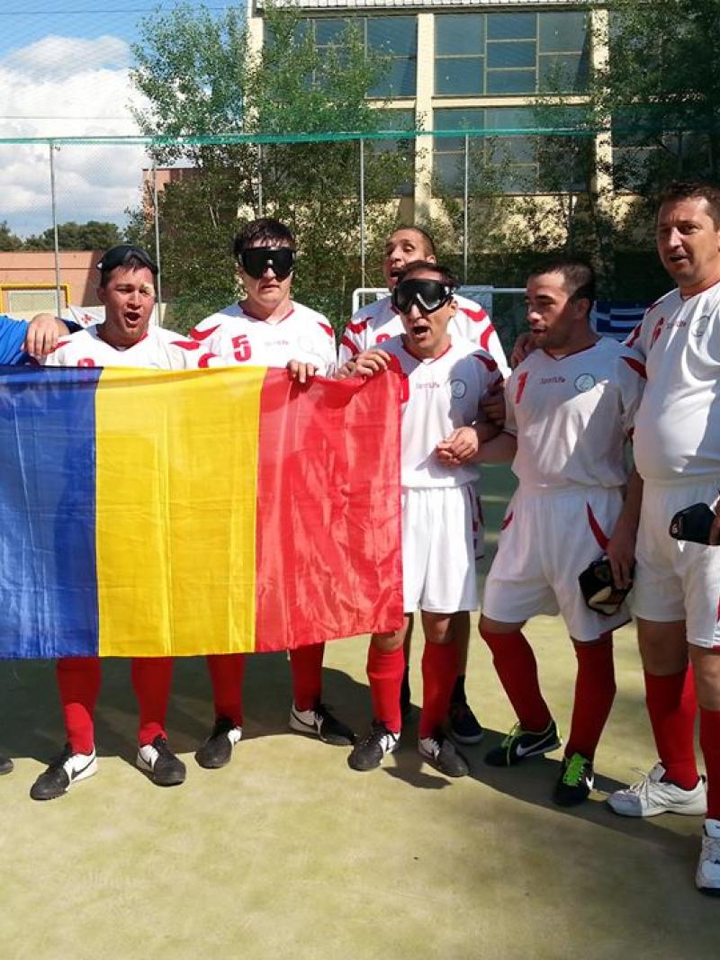Seven men, some of them blindfolded hold a Romanian flag, celebrate.