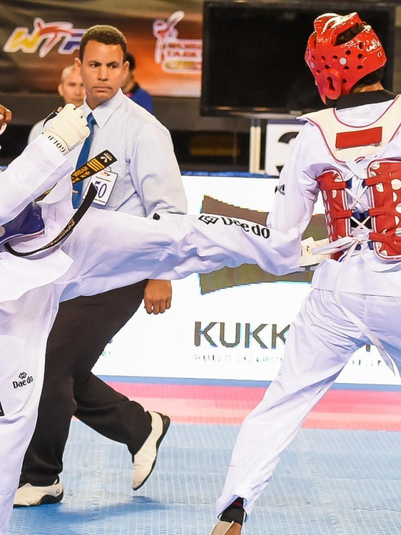 A taekwondo athlete kicks another taekwondo athlete