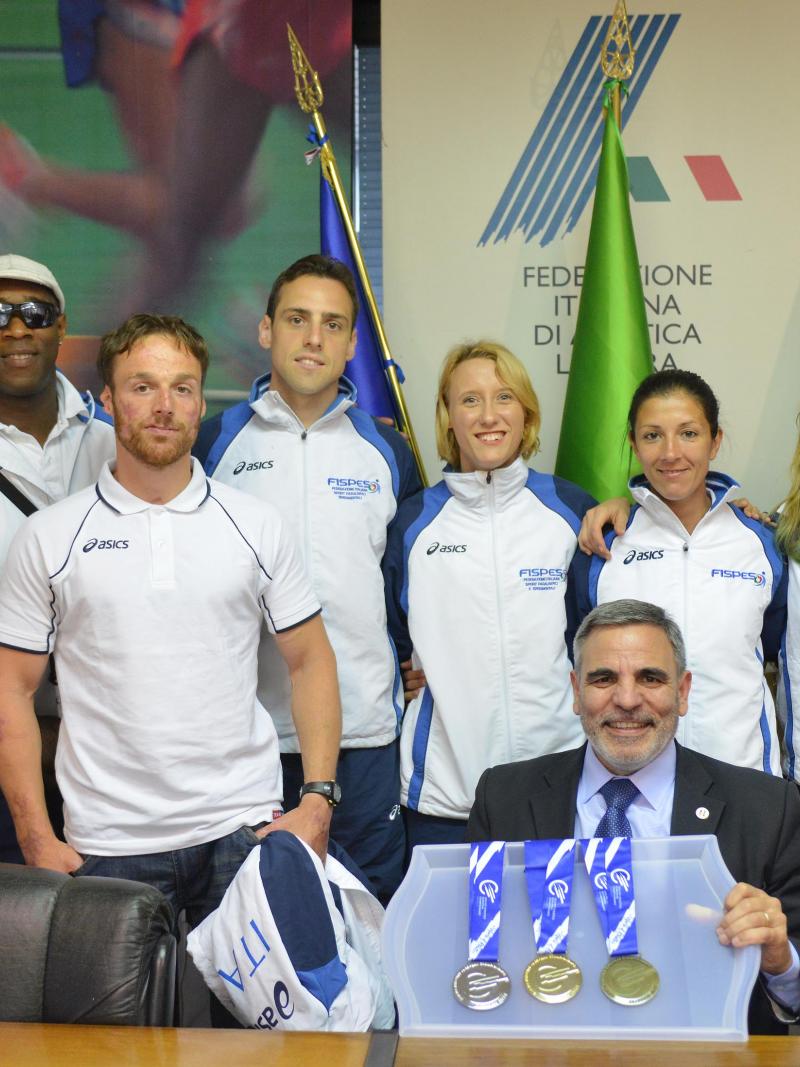 Group of athletes together with an older man showing medals