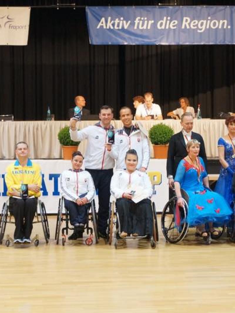 Group picture of people standing and in wheelchairs, showing medals