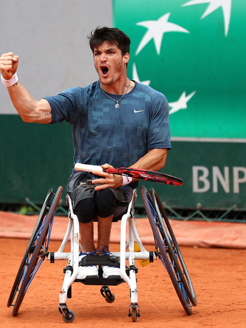 Man in wheelchair on tennis court, celebrating