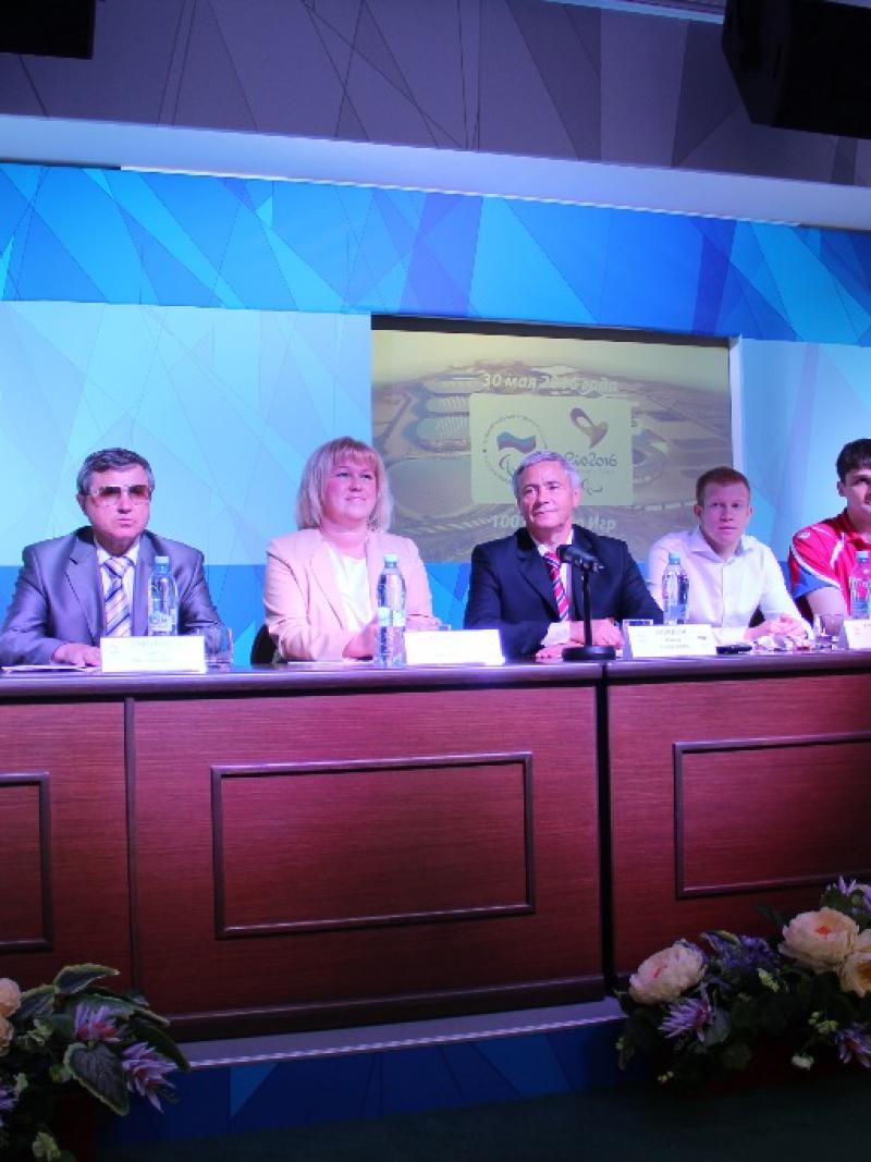 Seven members of the Russian Paralympic Comittee sitting at a desk at a press conference. 