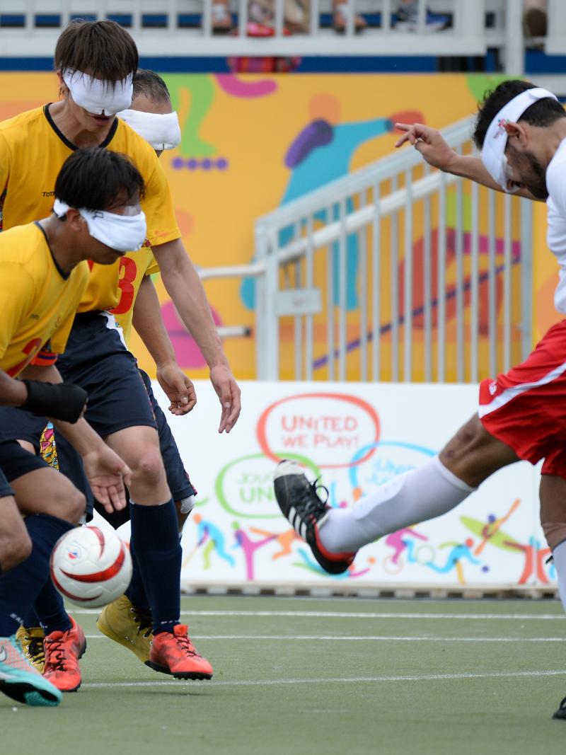 Three blind athletes playing football on a field at the Parapan American Games