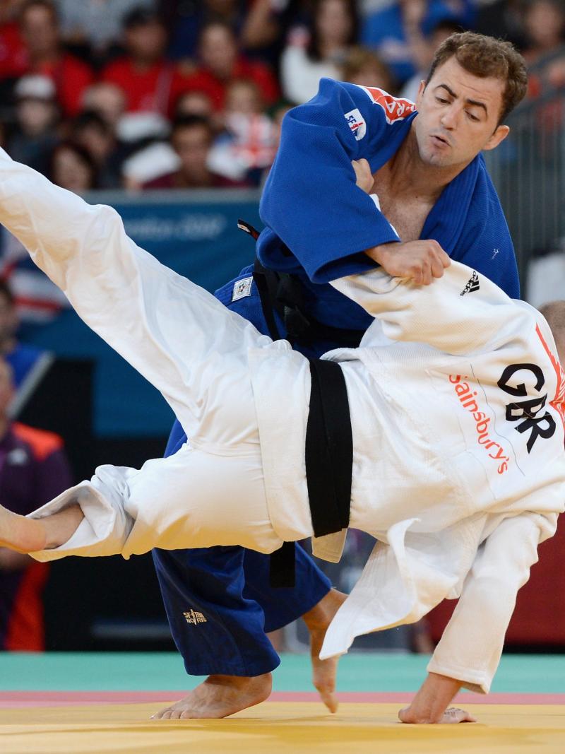 Two judo athletes fighting on a tatami or judo mat.