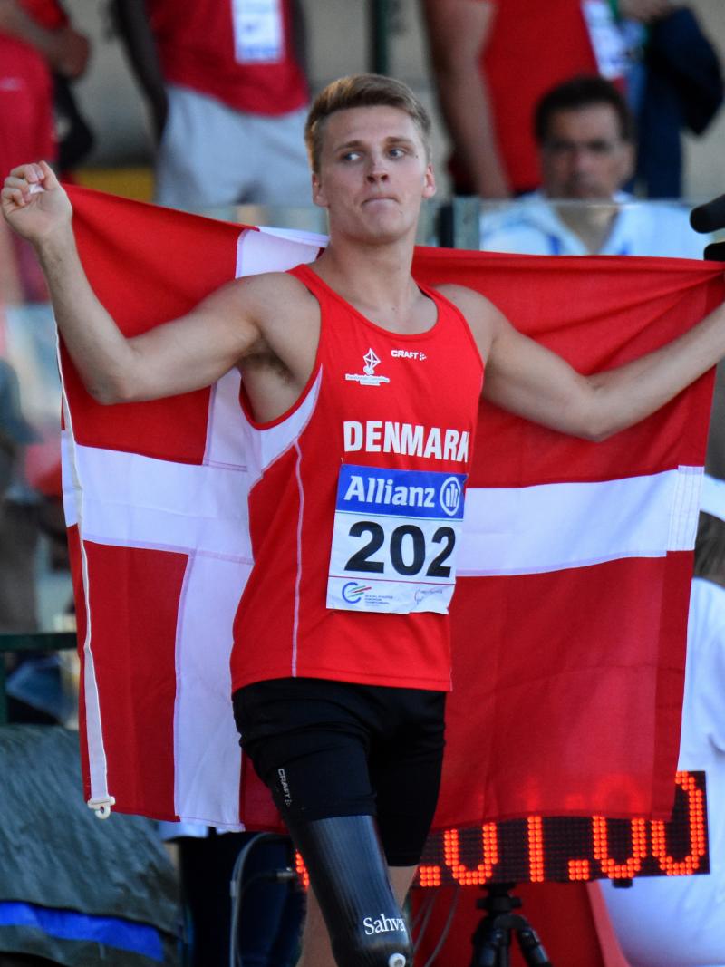 Man in red jersey celebrating with a Danish flag