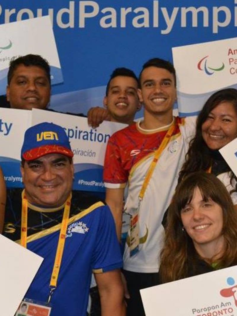 Group picture of four people, smiling and holding signs with 'ProudParalympian'