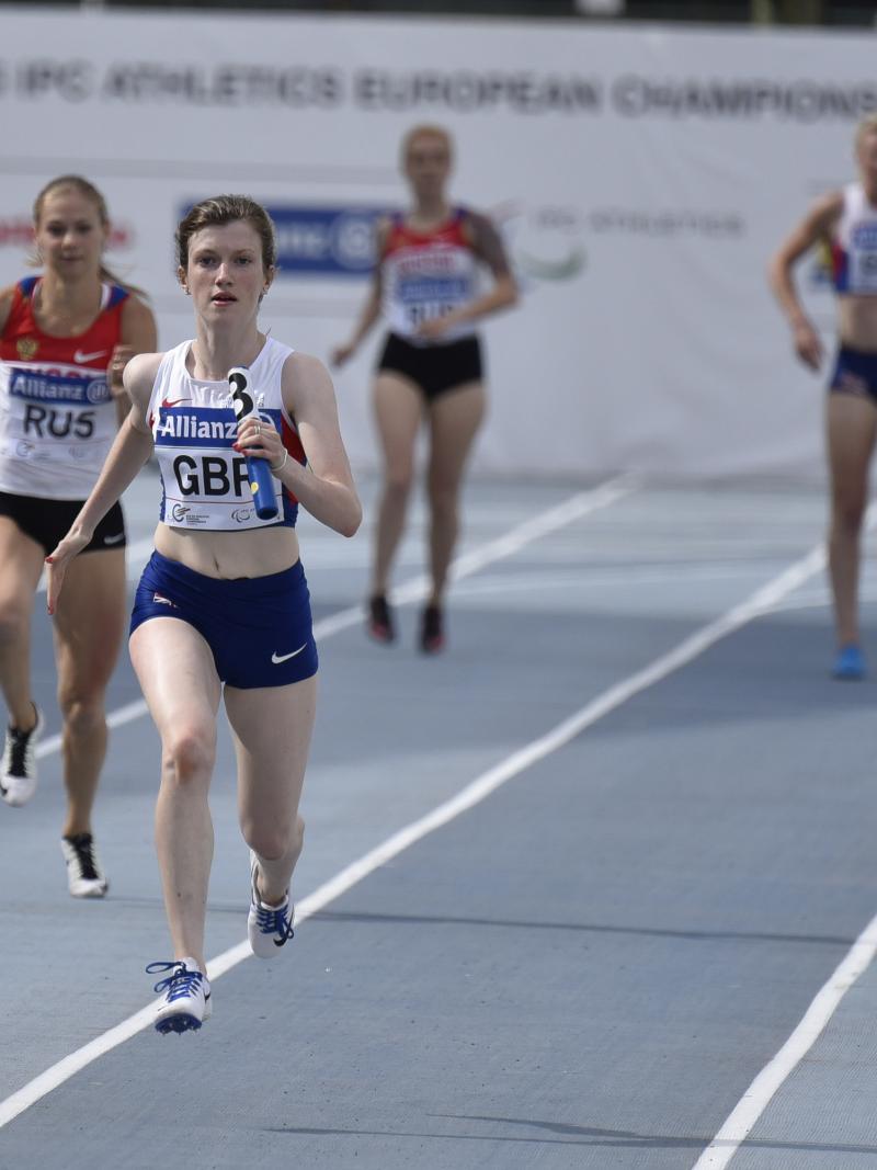 Two women running on a blue track
