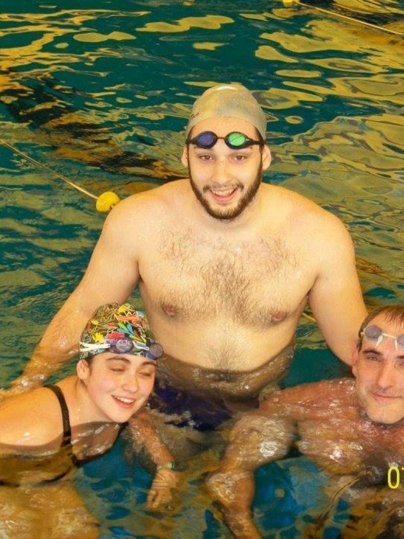 Three people in a pool, smiling to the camera