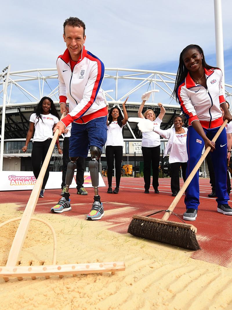 Two athletes cleaning the sand pit