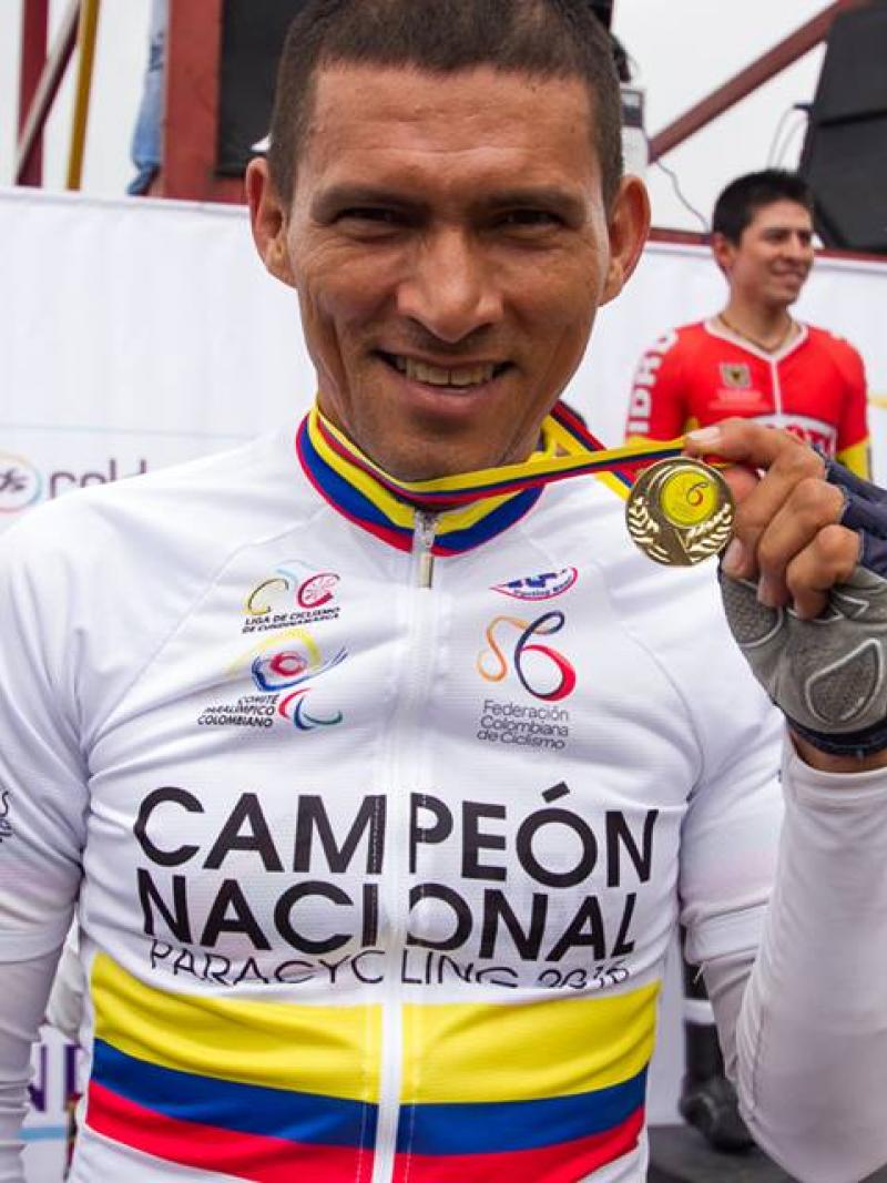 Man with cycling jersey showing his medal, smiling
