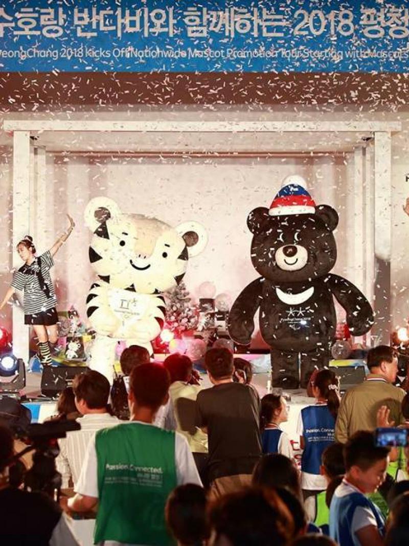 The PyeongChang 2018 full-sized mascots appear on stage in front of a crowd.