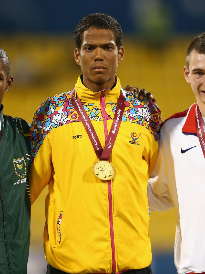 Colombian athlete Dixon Hooker poses on the podium with his gold medal next to the silver and bronze medallists.