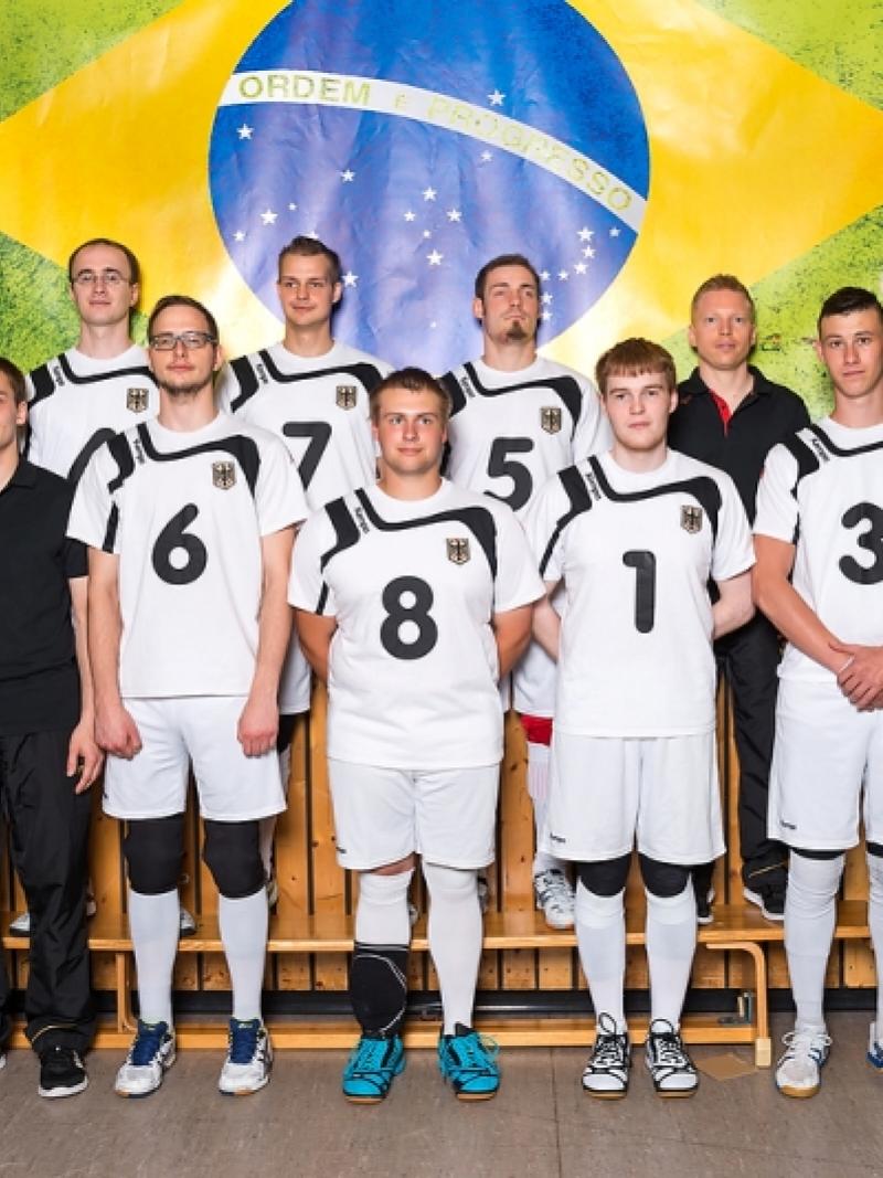 The German goalball team stands in front of a Brazilian flag.