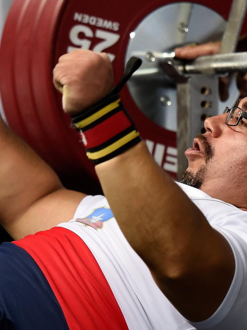 Chilean powerlifter Juan Carlos Garrido is on the bench and raises his hands celebrating his win.