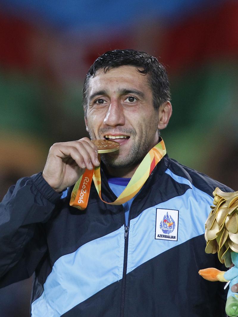 a man bites his medal in celebration